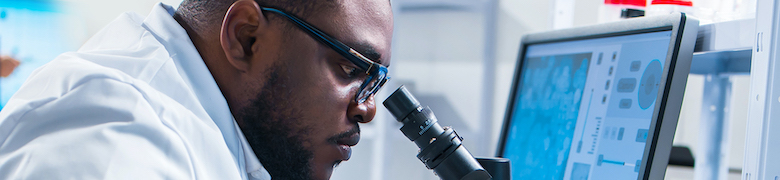 scientist looking through a microscope in a lab