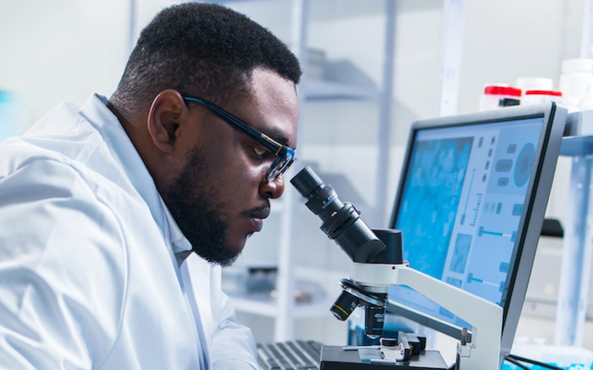 scientist looking through a microscope in a lab