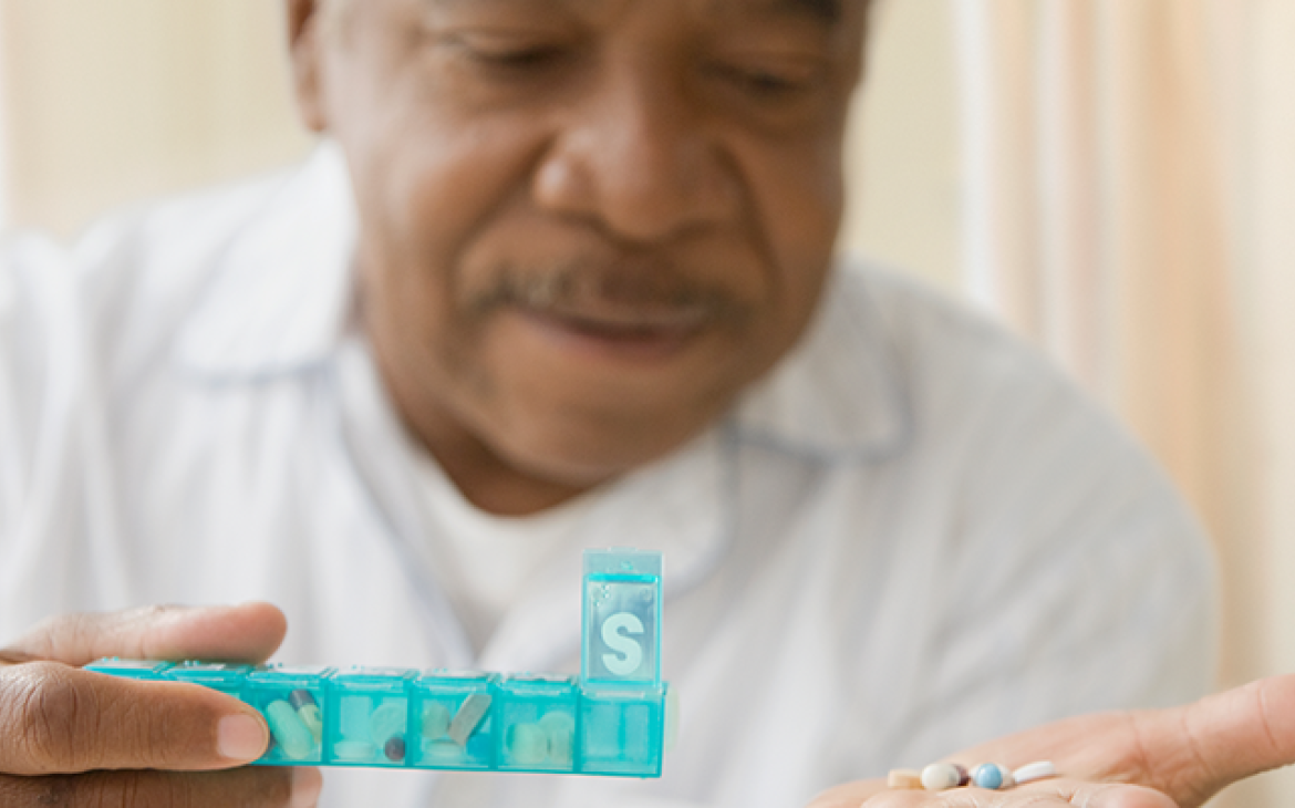 Man with a weekly pill organizer holding medicines